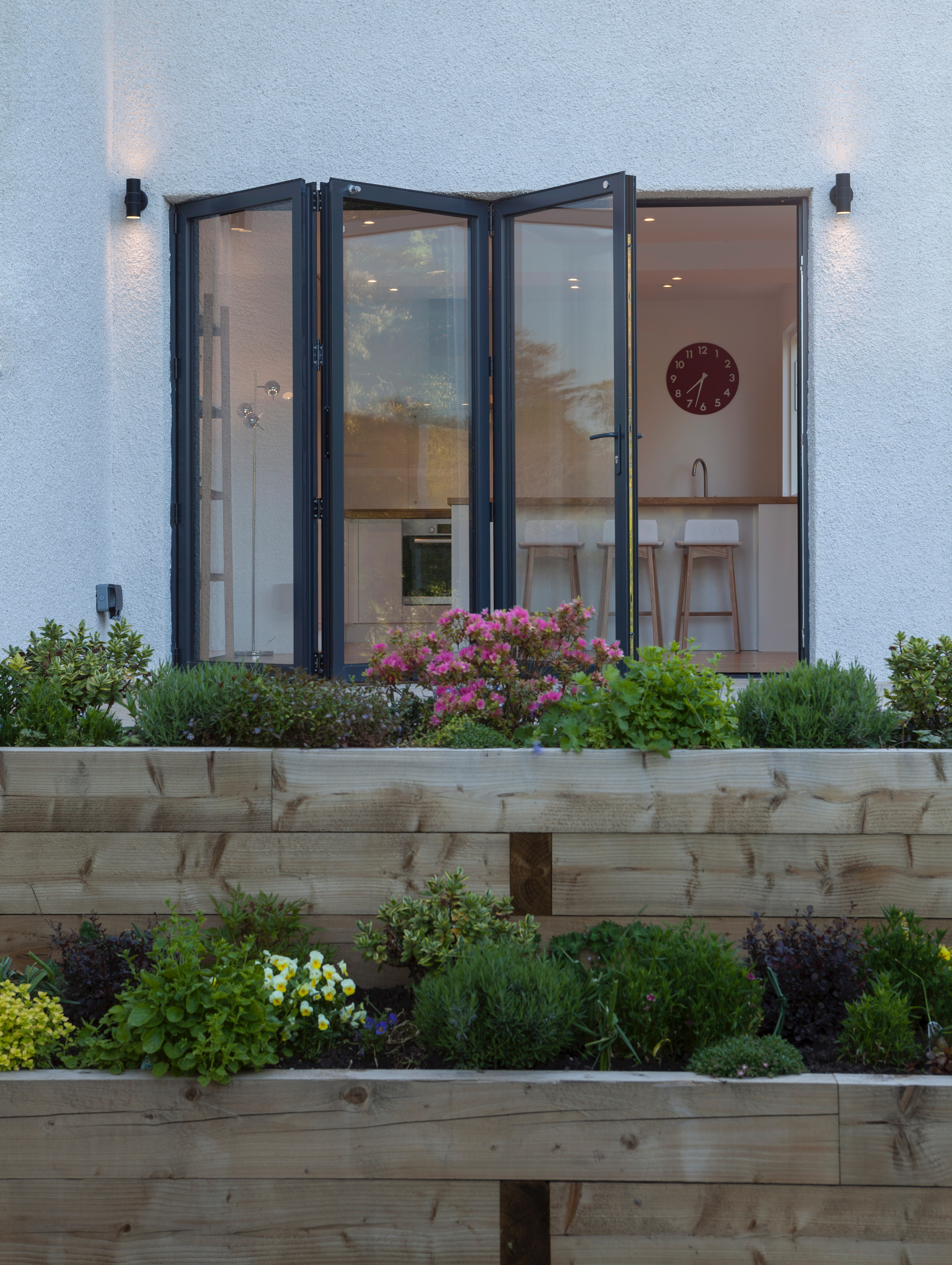 stepped flower beds leading to raised terrace with folding door access