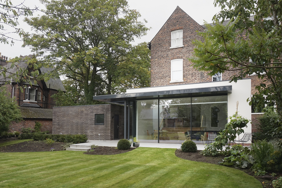 garden view of glazed extension with flat roof and new blue brick garage